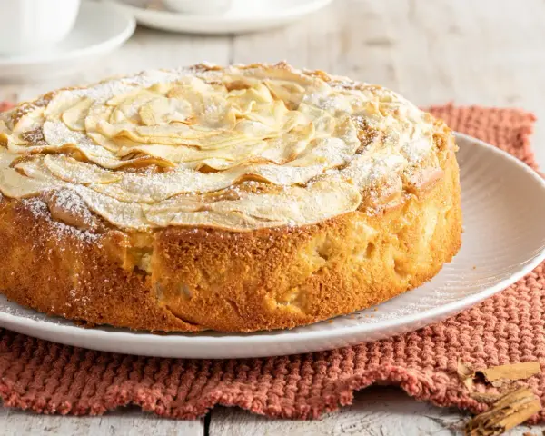 Deliziosa torta di mele senza burro, con mele a rosa sulla superficie e una spolverata di zucchero a velo. Perfetta per la colazione o la merenda.