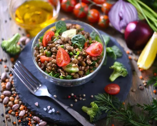 Un'insalata di lenticchie fresca e colorata, con pomodorini, cetrioli e spinacini, pronta per essere gustata.