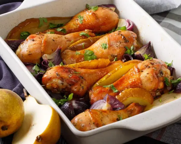 Cosce di pollo al forno dorate con pere, cipolle rosse e prezzemolo, un piatto succulento e profumato.