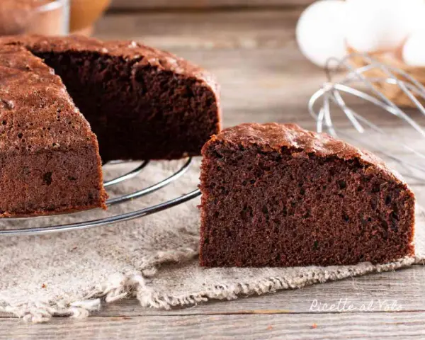 Una fetta di torta al cioccolato soffice e invitante, appena sfornata, su un tavolo di legno.