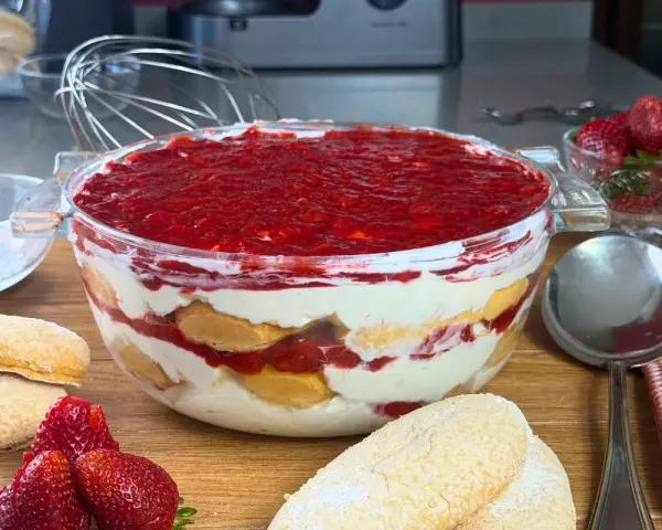 Un invitante tiramisù alle fragole in una ciotola di vetro, con savoiardi, crema e fragole fresche.