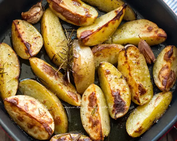 Patate al forno dorate e croccanti, condite con rosmarino e aglio, pronte per essere gustate.