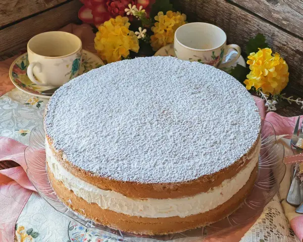 Torta Kinder Paradiso soffice e cremosa, cosparsa di zucchero a velo, pronta per essere gustata con un tè.