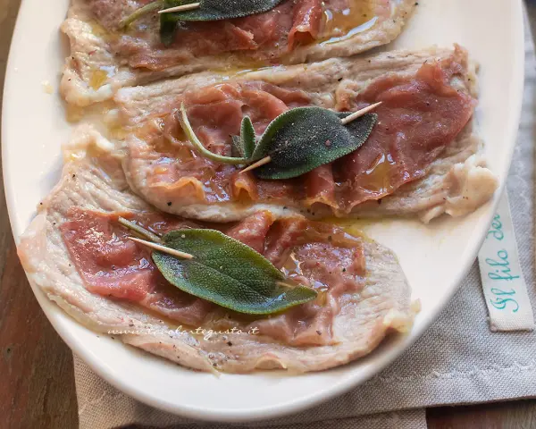 Saltimbocca alla romana: fettine di vitello con prosciutto crudo e salvia, condite con olio e pepe.