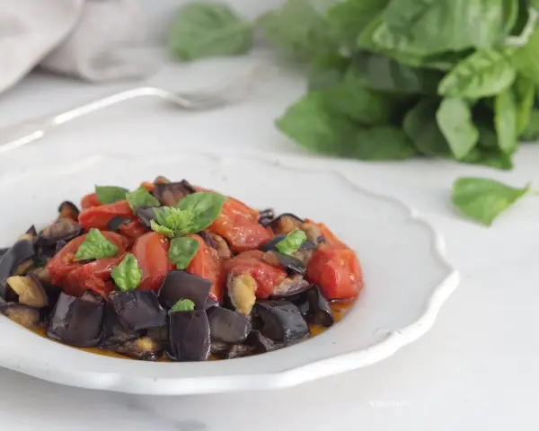 Un piatto invitante di melanzane a funghetto con pomodorini e basilico fresco, pronto per essere gustato.