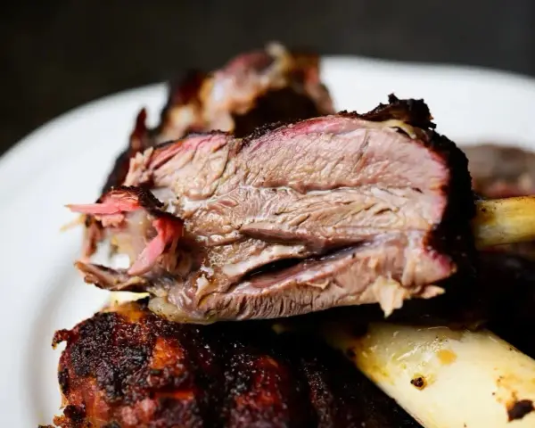 Succulento stinco di maiale affumicato, cotto lentamente fino a diventare tenerissimo. La carne rosa e succosa si stacca dall'osso.