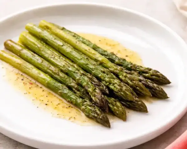 Asparagi in padella, cotti alla perfezione e conditi con un leggero sughetto.