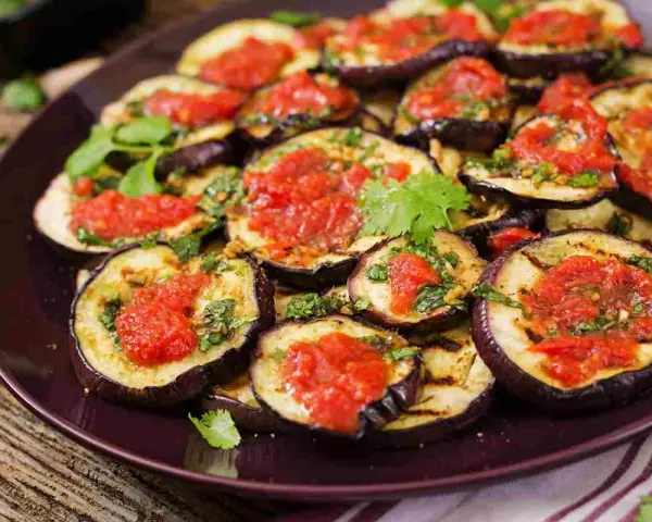 Fette di melanzane grigliate condite con salsa di pomodoro e basilico, un piatto invitante di melanzane alla pizzaiola.