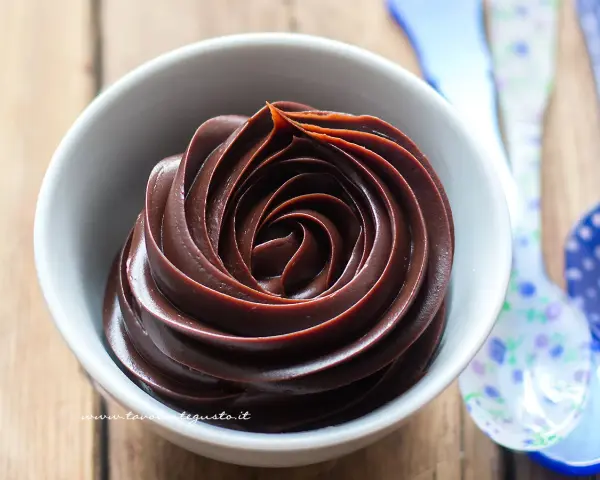 Una ciotola bianca piena di lucida ganache al cioccolato, disposta a spirale.