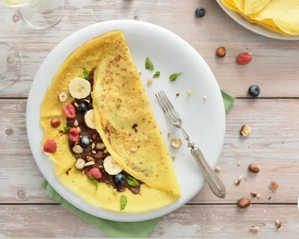 Deliziosa crepes senza glutine ripiena di crema al cioccolato, frutta fresca e nocciole. Un piacere per tutti i sensi.