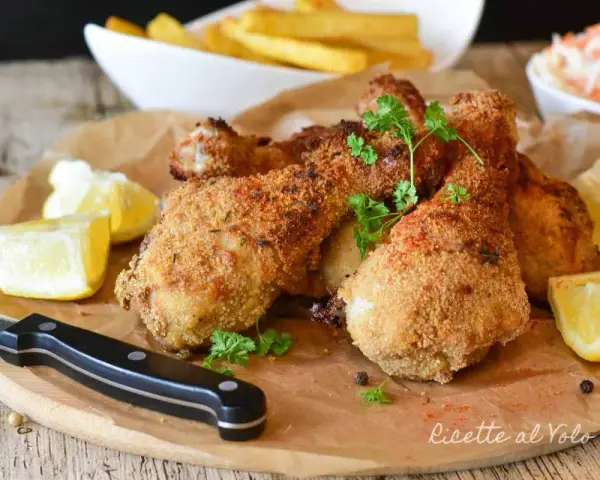 Fusi di pollo in friggitrice ad aria, dorati e croccanti, serviti con spicchi di limone e prezzemolo fresco.