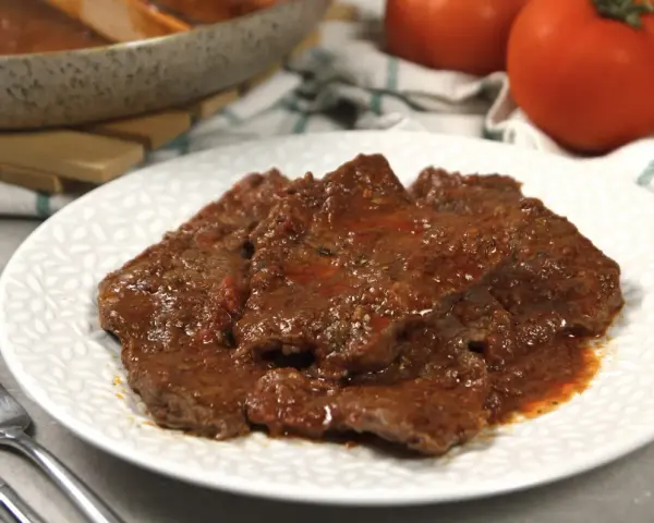 Piatto di carne alla pizzaiola morbida, succulenta e profumata, con pomodoro e spezie.