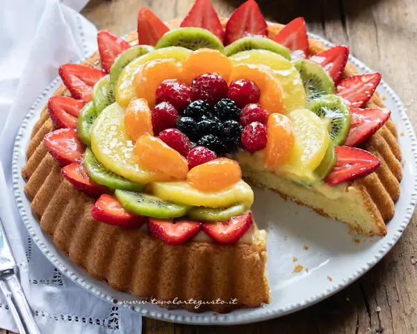 Una deliziosa crostata morbida alla frutta, con fragole, kiwi, mandarini e frutti di bosco, su una base soffice e crema pasticcera.