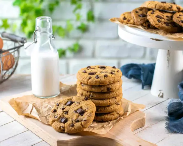 Una pila di deliziosi biscotti con gocce di cioccolato, pronti per essere gustati con un bicchiere di latte.