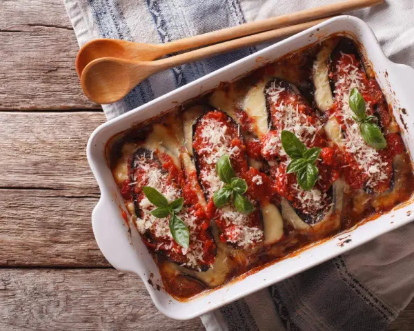 Parmigiana di melanzane appena sfornata, con melanzane, pomodoro, mozzarella filante e basilico fresco.