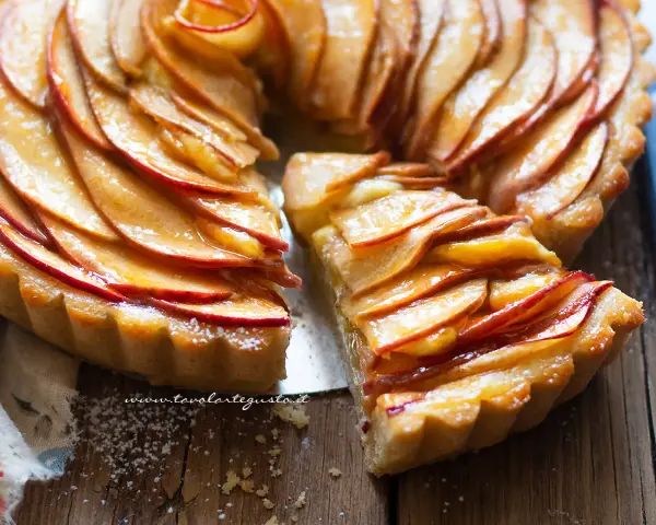 Una fetta di crostata di mele lucida e dorata, con le mele disposte a spirale su una base friabile.