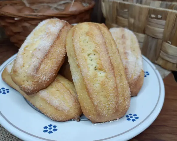 Biscotti da inzuppo dorati e zuccherati, perfetti per la colazione o la merenda. Sullo sfondo, un cestino di uova e un altro intrecciato.