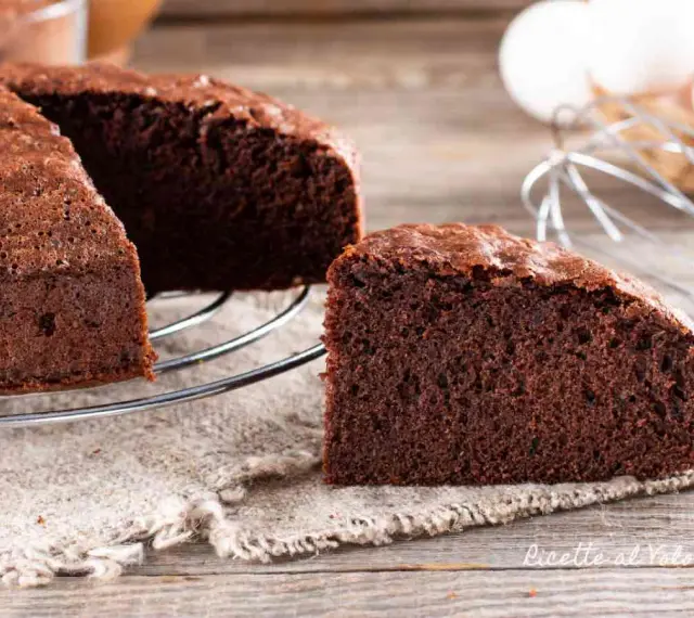 Una fetta di torta al cioccolato soffice e invitante, appena sfornata, su un tavolo di legno.