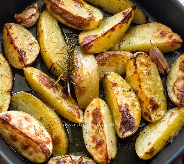 Patate al forno dorate e croccanti, condite con rosmarino e aglio, pronte per essere gustate.