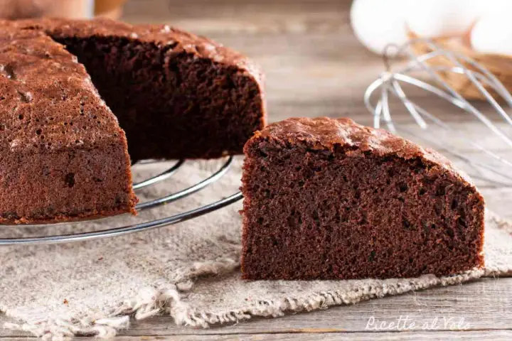 Una fetta di torta al cioccolato soffice e invitante, appena sfornata, su un tavolo di legno.
