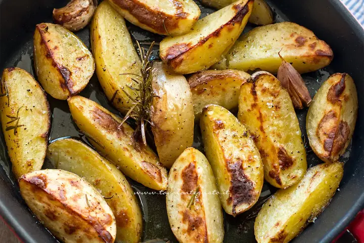 Patate al forno dorate e croccanti, condite con rosmarino e aglio, pronte per essere gustate.