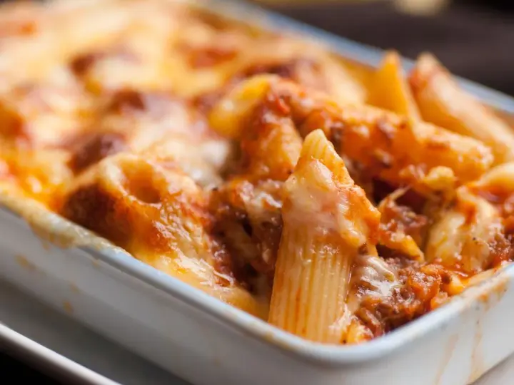 Penne al forno con sugo di pomodoro e mozzarella filante, un classico della pasta alla sorrentina.