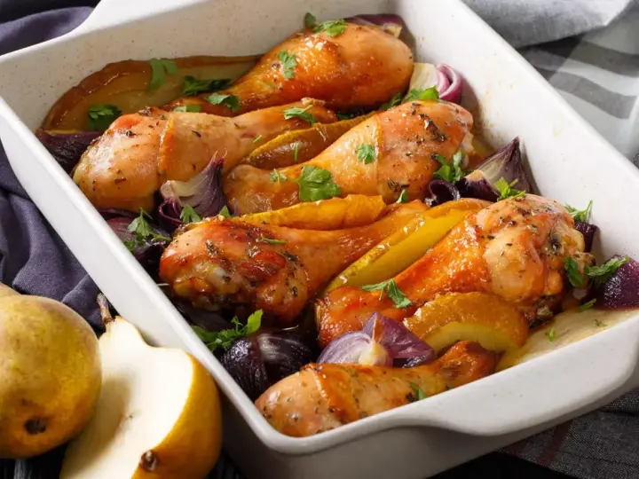 Cosce di pollo al forno dorate con pere, cipolle rosse e prezzemolo, un piatto succulento e profumato.