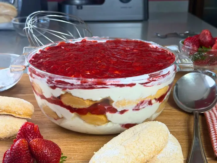 Un invitante tiramisù alle fragole in una ciotola di vetro, con savoiardi, crema e fragole fresche.