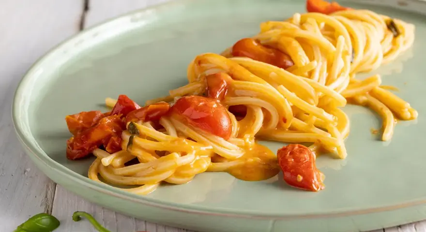 Spaghetti allo scarpariello fumanti, con pomodorini succosi e un tocco piccante, pronti per essere gustati.