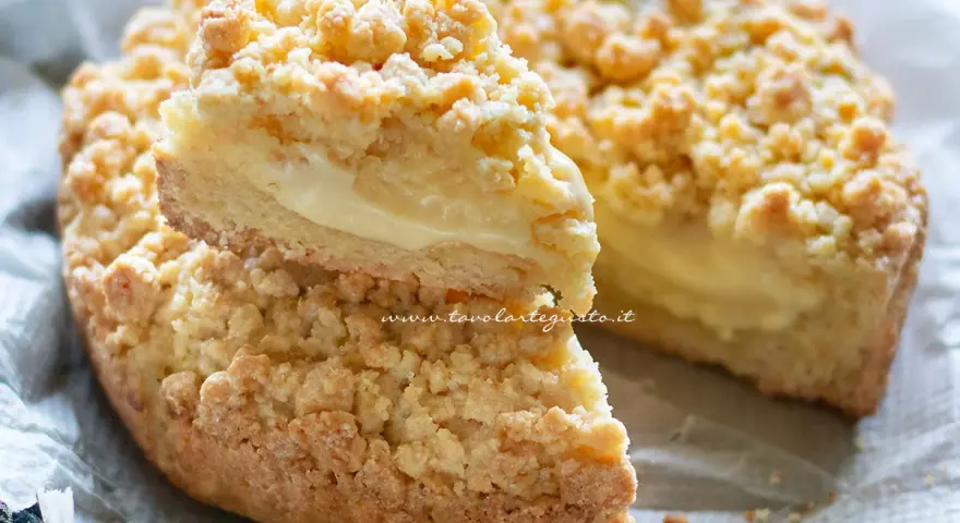 Sbriciolata alla crema, con la sua crosta dorata e il ripieno morbido, è un dolce che invita a un morso goloso.