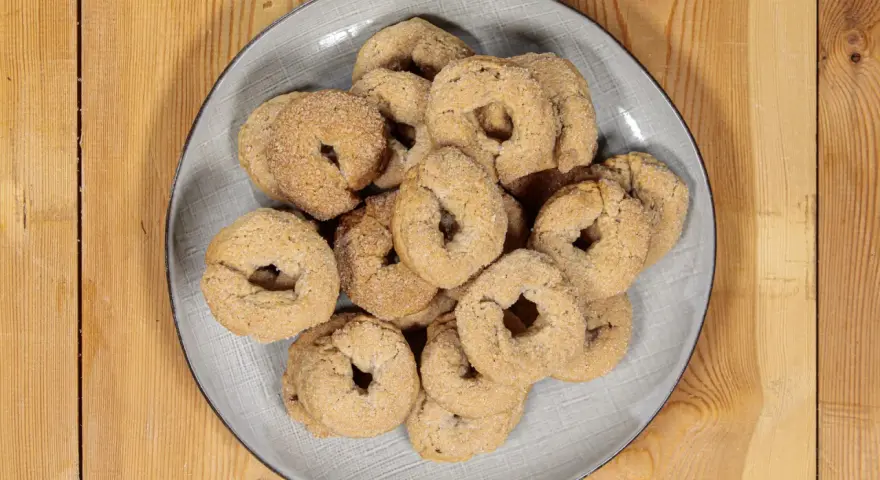 Piatto di ciambelline al vino, dolcetti friabili e dorati, perfetti per accompagnare un caffè o un tè.