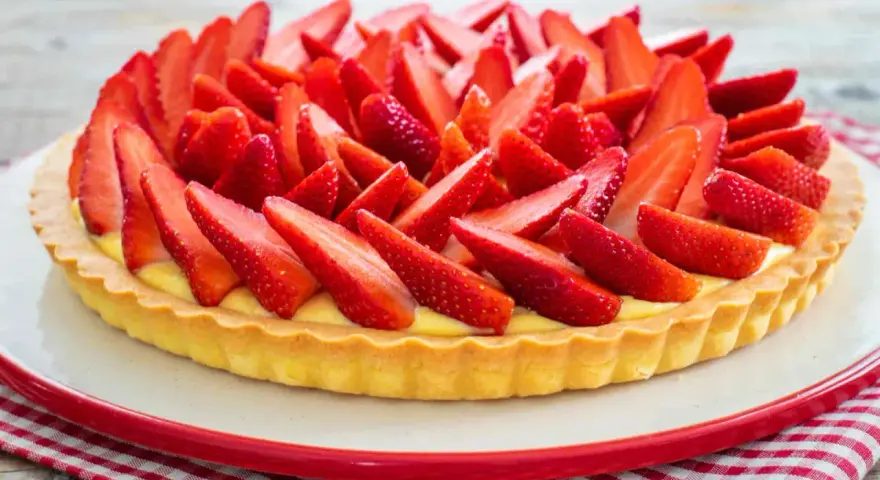 Una deliziosa crostata di fragole, con una base dorata e un ripieno cremoso, ricoperta da fragole fresche affettate.