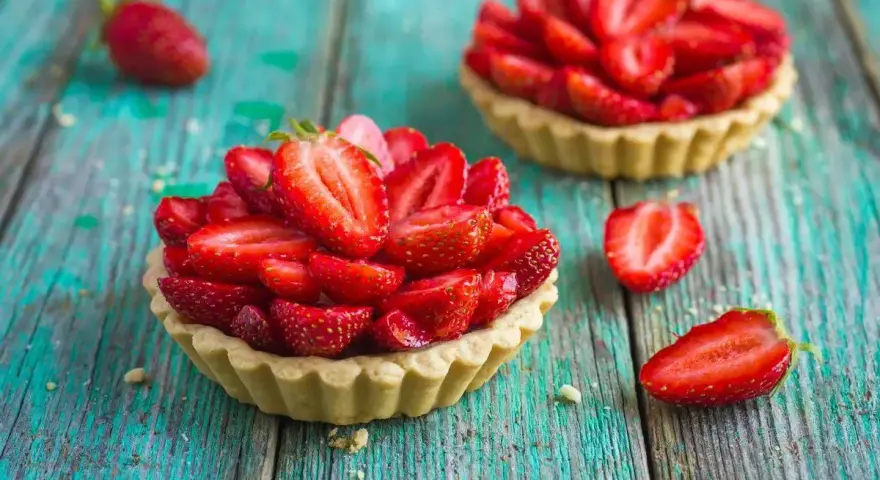 Deliziosi dolci con fragole fresche, disposti su un tavolo di legno turchese.