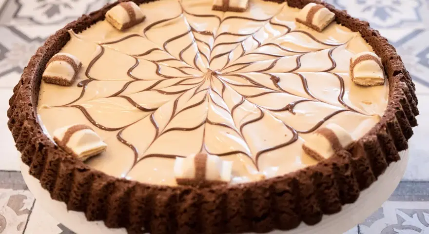 Torta Kinder Bueno con decorazione a ragnatela in cioccolato e pezzi di wafer.
