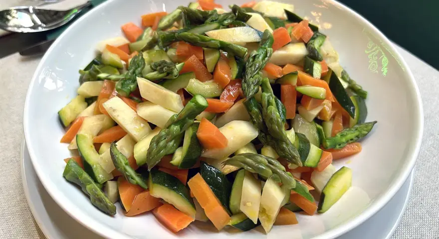 Un piatto invitante di verdure in padella: carote, zucchine e asparagi tagliati a pezzetti, cotti al punto giusto.