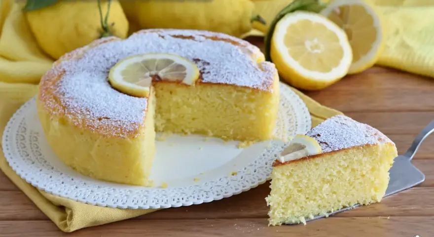 Una soffice torta ricotta e limone, spolverata di zucchero a velo e decorata con fettine di limone. Perfetta per una pausa golosa.