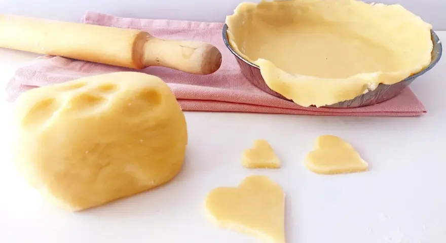 Impasto per pasta frolla senza glutine pronto per essere trasformato in dolci cuori e una crostata.