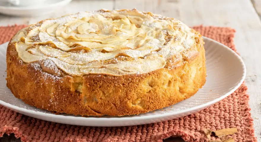 Deliziosa torta di mele senza burro, con mele a rosa sulla superficie e una spolverata di zucchero a velo. Perfetta per la colazione o la merenda.