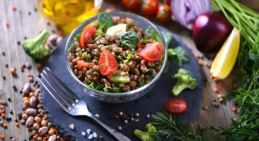 Un'insalata di lenticchie fresca e colorata, con pomodorini, cetrioli e spinacini, pronta per essere gustata.