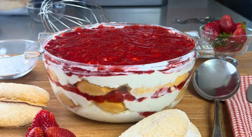 Un invitante tiramisù alle fragole in una ciotola di vetro, con savoiardi, crema e fragole fresche.