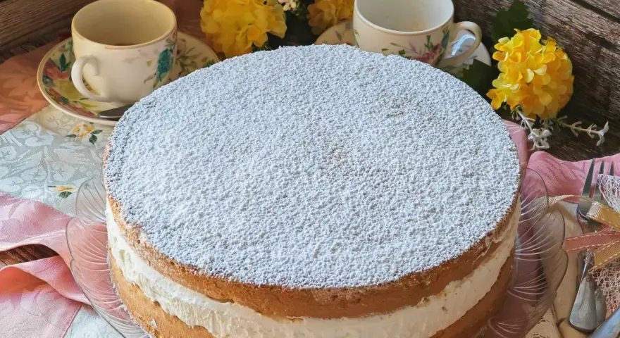 Torta Kinder Paradiso soffice e cremosa, cosparsa di zucchero a velo, pronta per essere gustata con un tè.