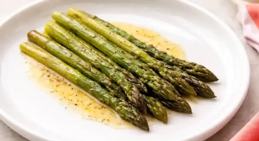 Asparagi in padella, cotti alla perfezione e conditi con un leggero sughetto.