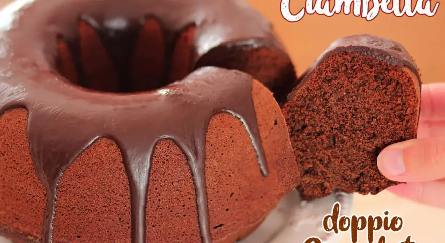 Ciambellone al cioccolato con glassa fondente che cola. Una fetta viene sollevata, mostrando la morbidezza dell'impasto.