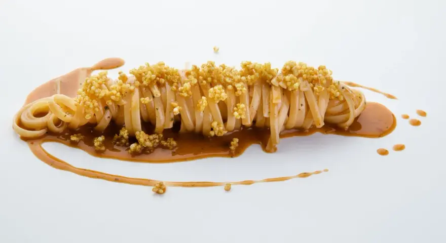 Pasta con carciofi Cannavacciuolo, un piatto elegante con pasta lunga, salsa cremosa e croccanti germogli di quinoa.