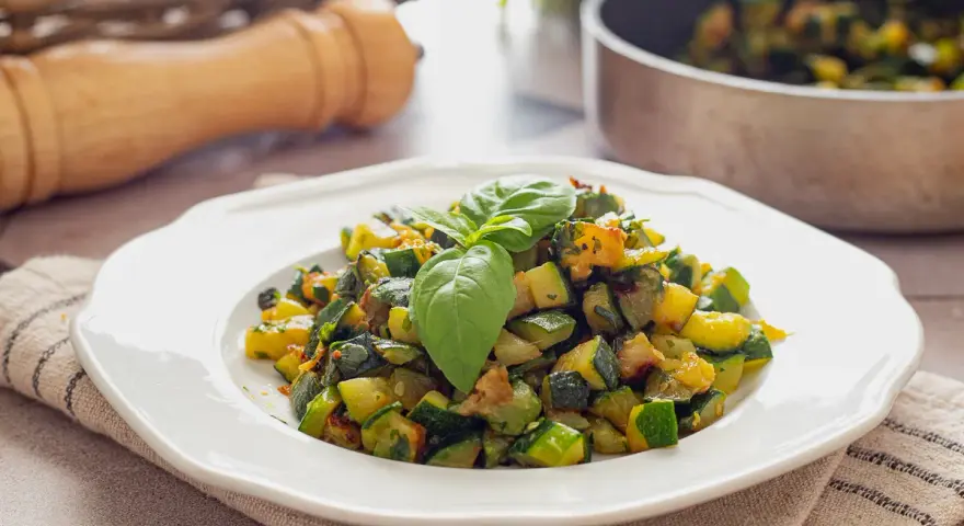 Zucchine in padella, un contorno saporito e colorato, guarnito con basilico fresco.