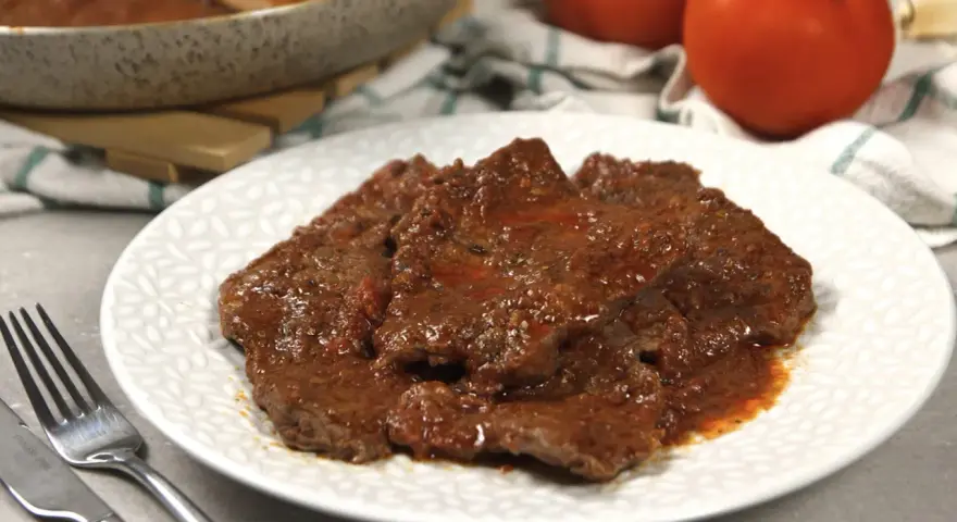 Piatto di carne alla pizzaiola morbida, succulenta e profumata, con pomodoro e spezie.