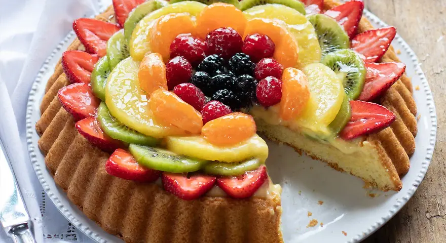 Una deliziosa crostata morbida alla frutta, con fragole, kiwi, mandarini e frutti di bosco, su una base soffice e crema pasticcera.