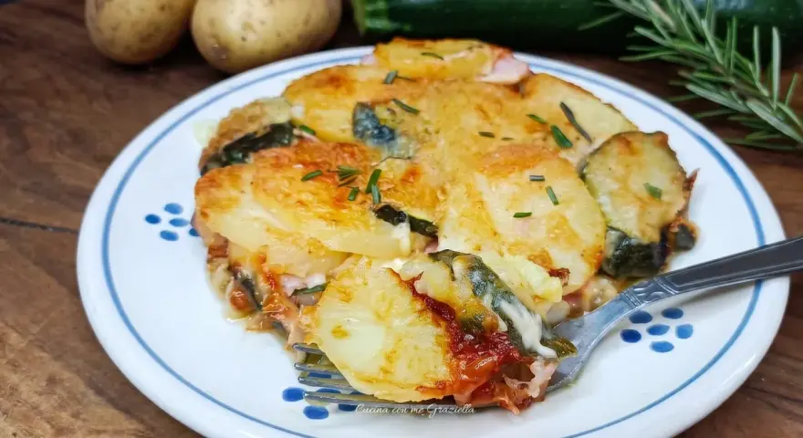 Piatto invitante di patate e zucchine al forno, dorate e filanti, con rosmarino fresco. Un contorno perfetto per ogni pasto.