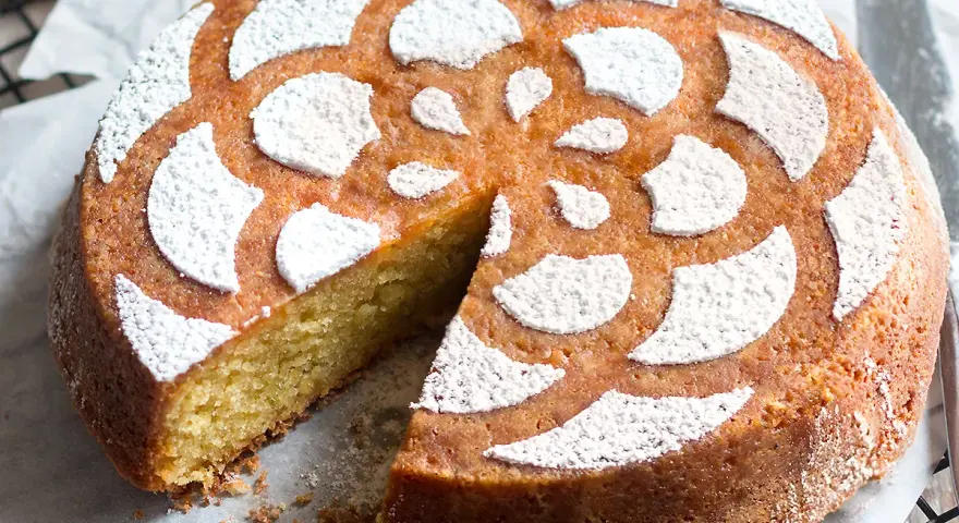 Torta soffice caprese al limone, decorata con zucchero a velo a forma di fiore.
