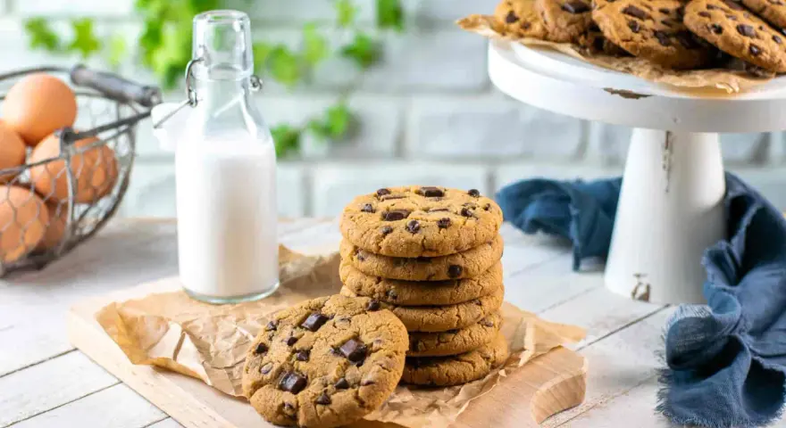 Una pila di deliziosi biscotti con gocce di cioccolato, pronti per essere gustati con un bicchiere di latte.